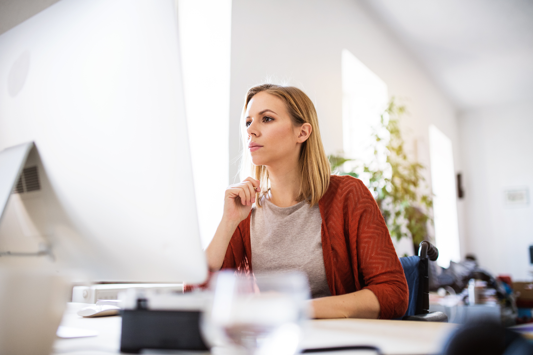 Businesswoman in wheelchair at the desk in her office.;