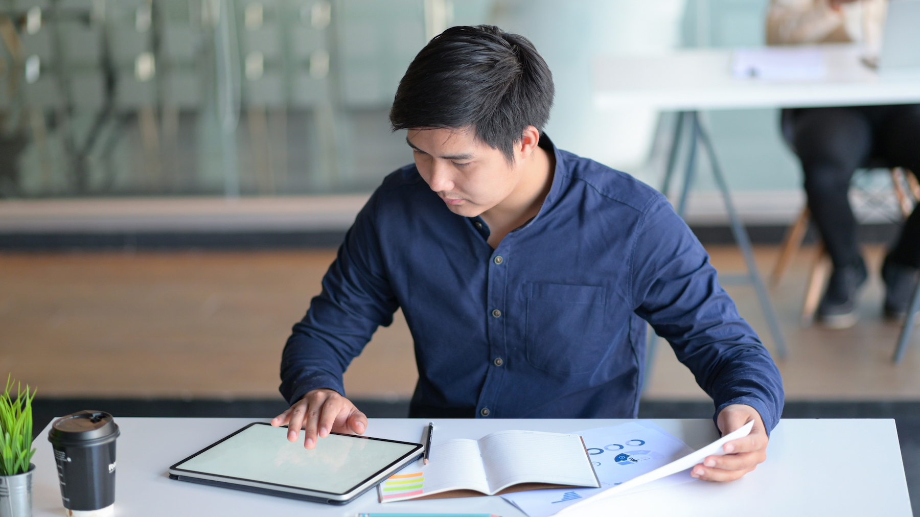 The male office worker is working with a tablet at a modern office.