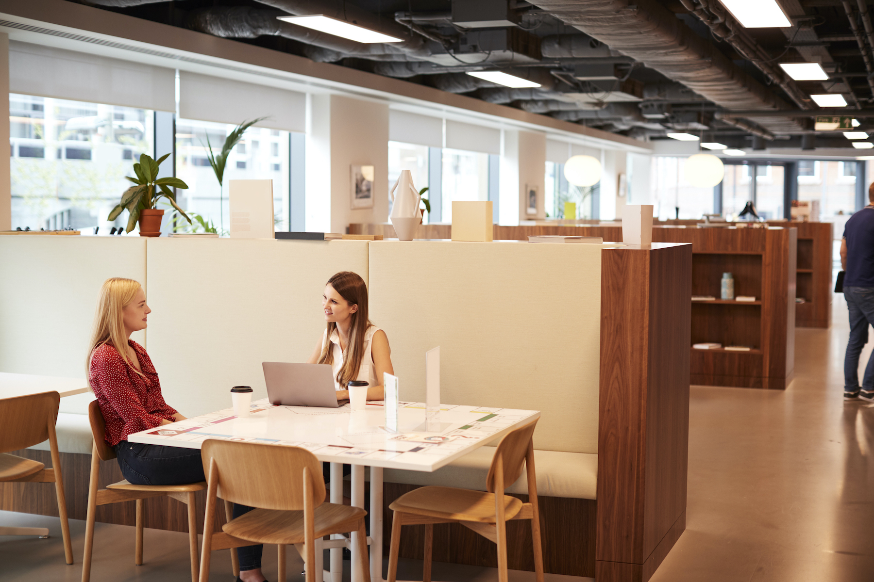 Two Young Businesswomen Having Informal Interview In Cafeteria Area At Graduate Recruitment Assessment Day;